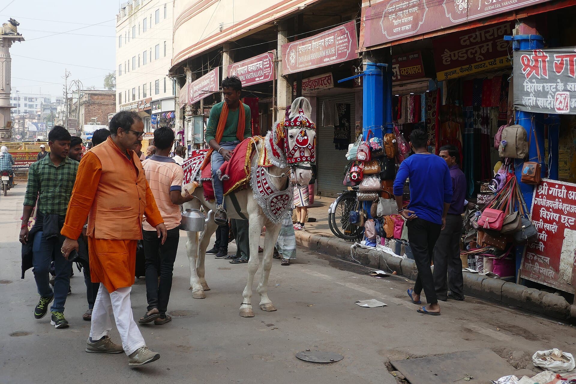 Baraat procession moving down a narrow street with dhol players ahead.